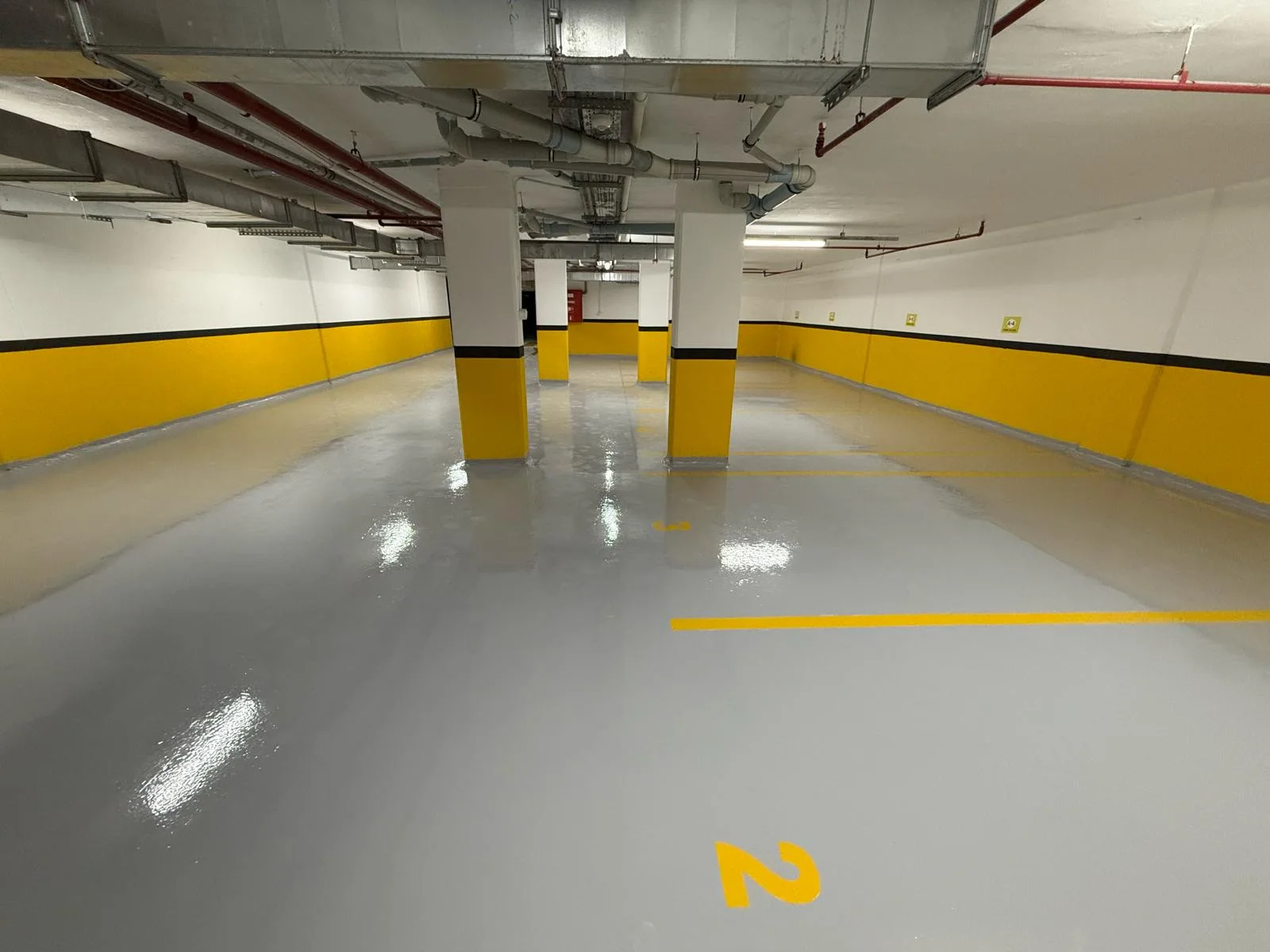 Kapalı otoparkta gri kaplama ve sarı kolonlar – Otopark epoksi zemin kaplama saha fotoğrafı